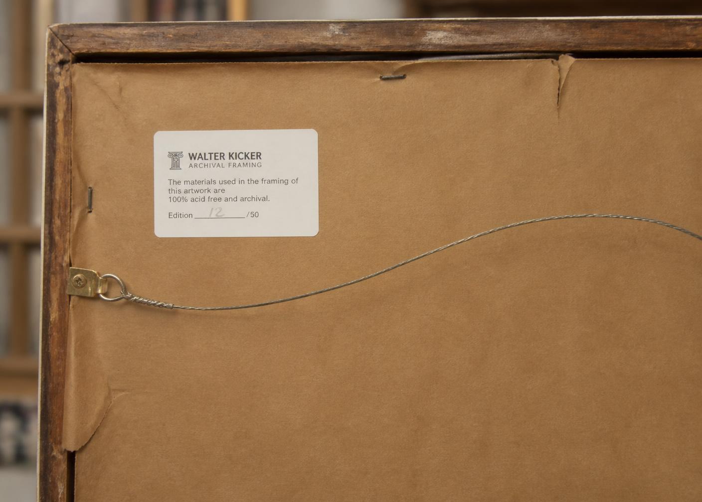 Reverse of a framed work showing an archival framing label with a handwritten edition number